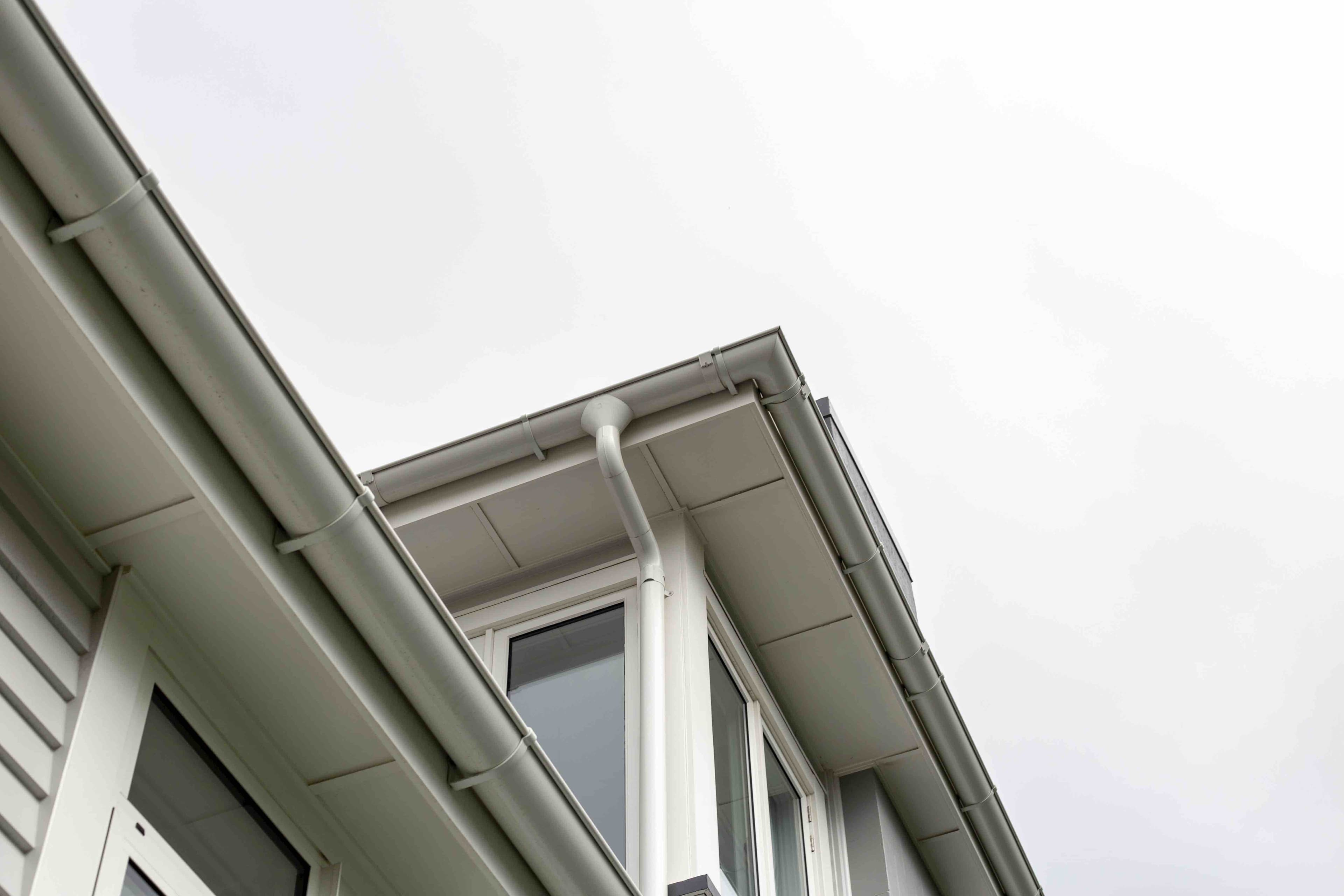 Person cleaning a gutter on scaffolding