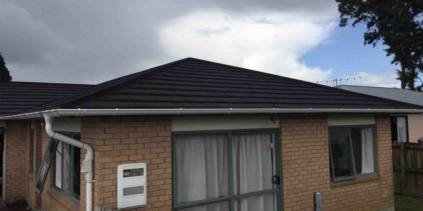 Person on roof with harness clearing a blocked gutter