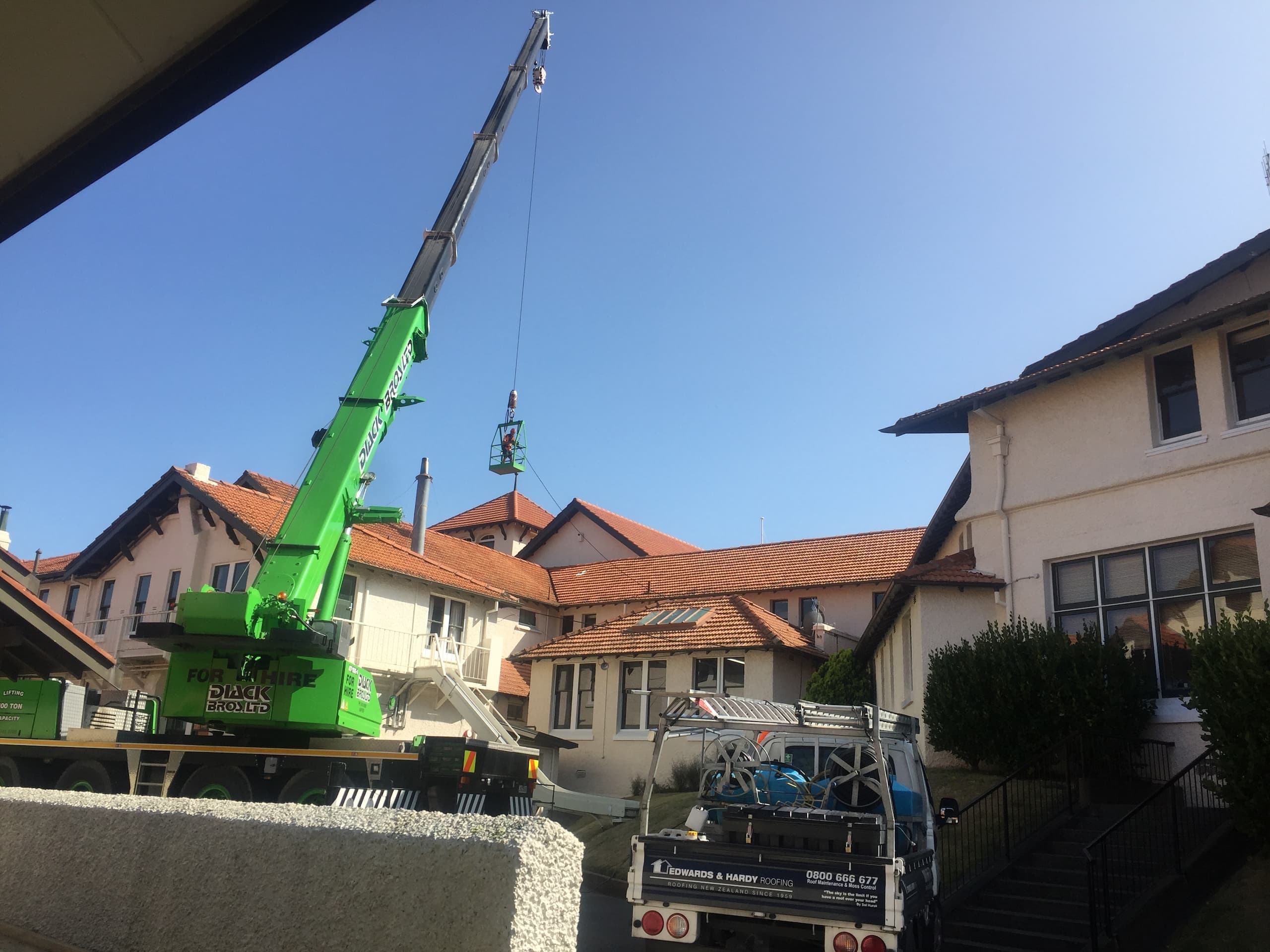 Roof Cleaning a Concrete Roof from a crane cage