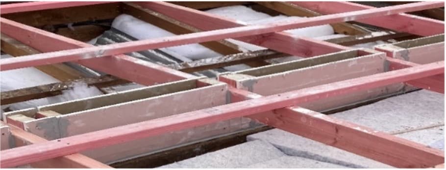 Open roof structure showing a party wall junction and fire wall gap remediation area beneath timber battens