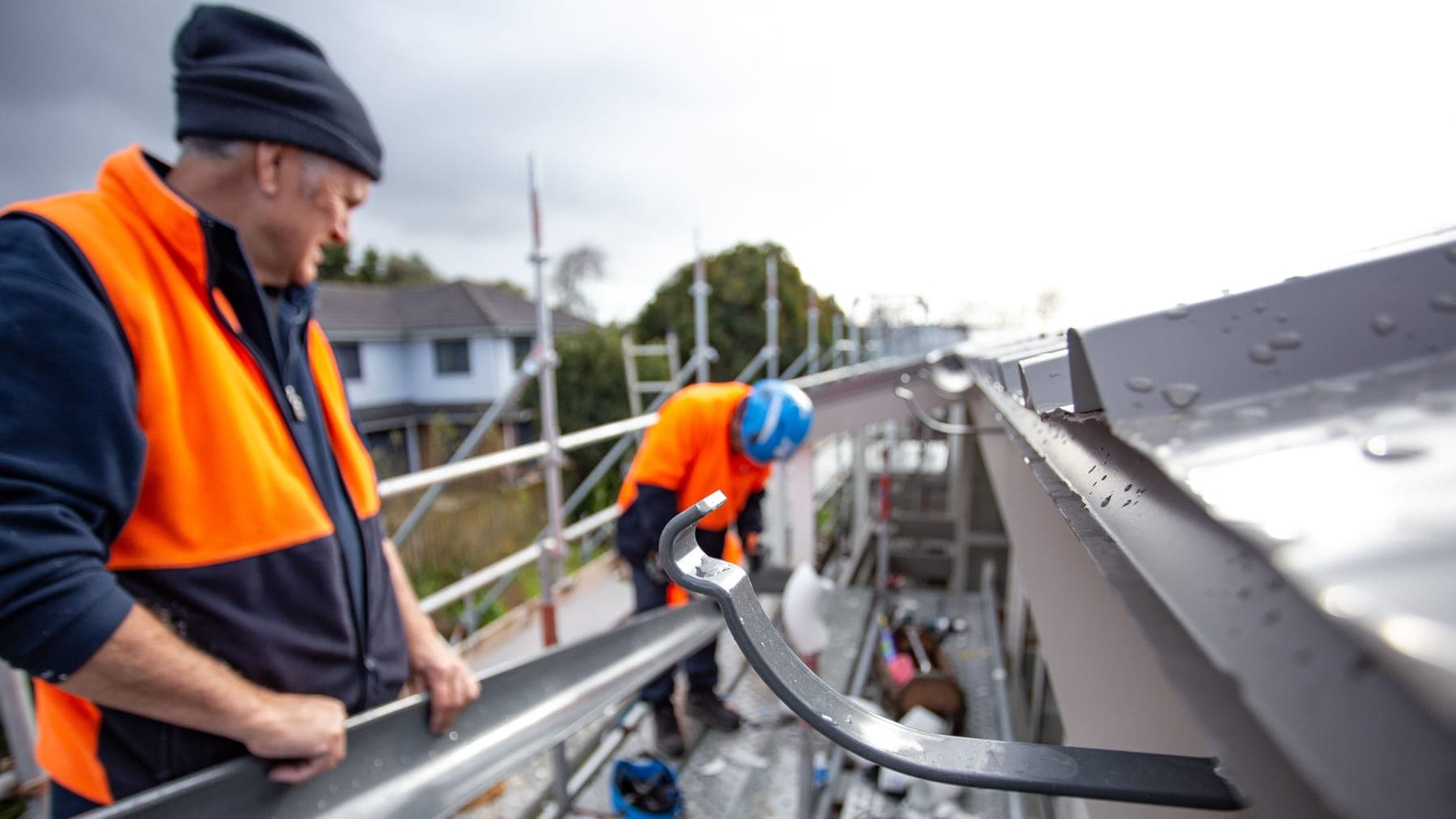 Person installing new gutters on a residential home in New Zealand