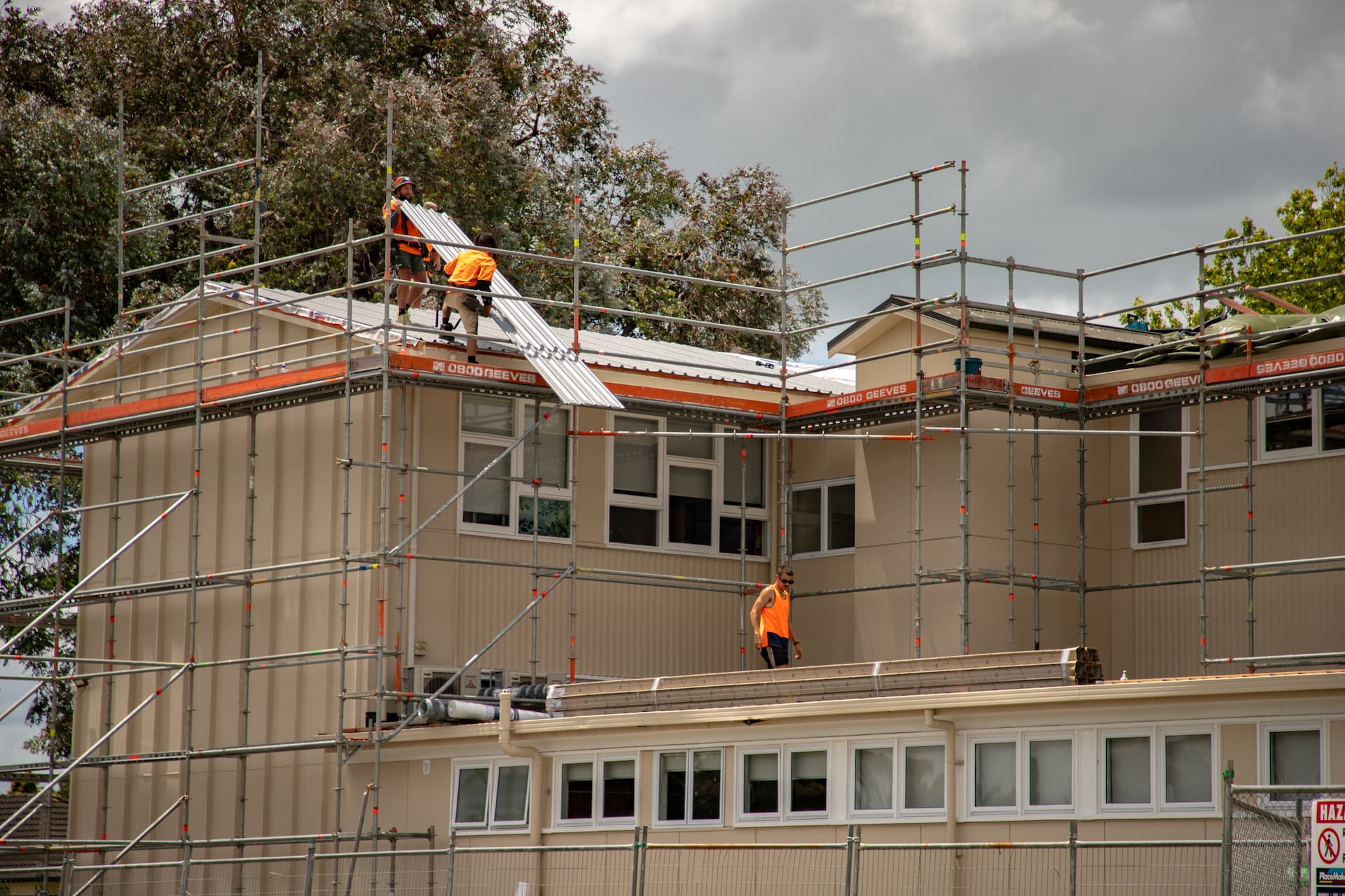 Edwards & Hardy team of 17 roofers gathered in front of the company van at Fairfield College, with scaffolding and the school building in the background