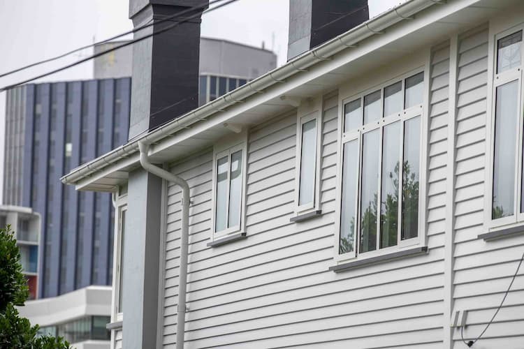Person on roof with harness clearing a blocked gutter