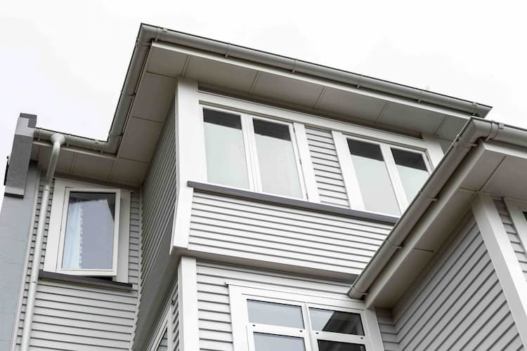 Person on roof with harness clearing a blocked gutter