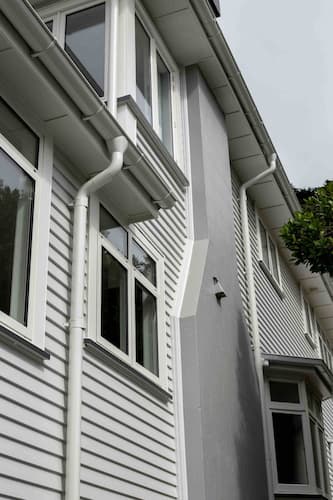Person on roof with harness clearing a blocked gutter