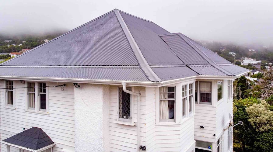 Person on roof with harness clearing a blocked gutter