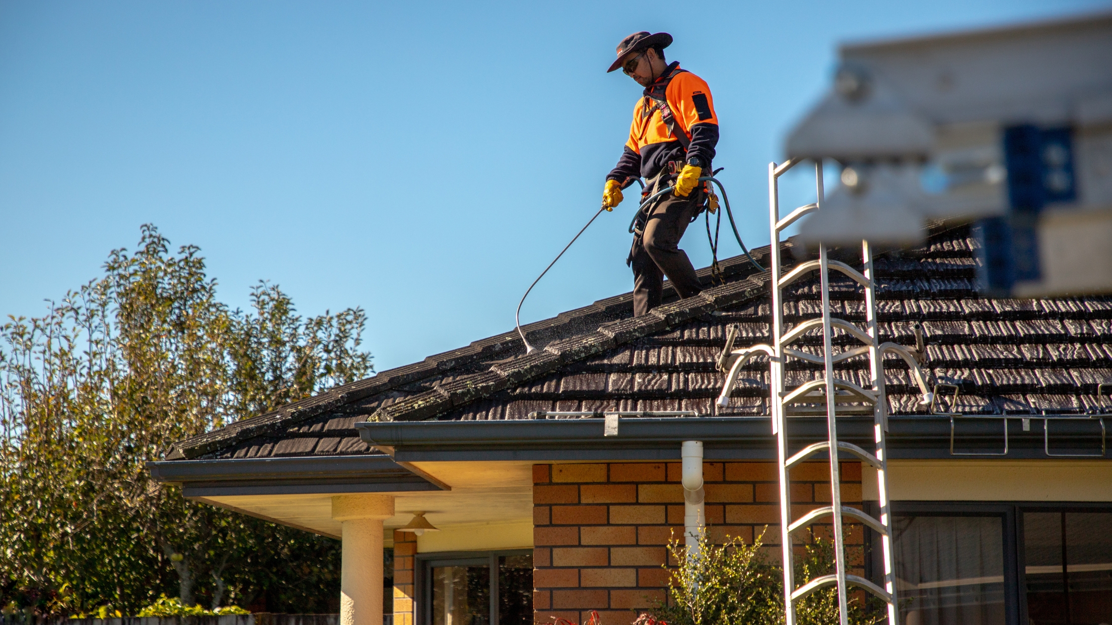 Professional roof specialist applying moss treatment to a tiled roof in New Zealand