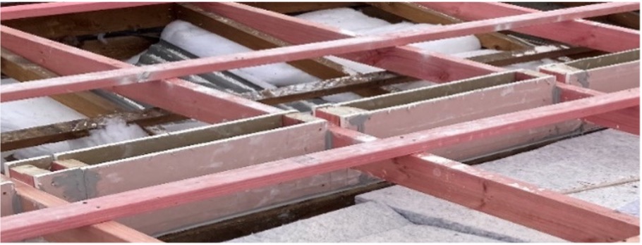 Open roof structure showing a party wall junction and fire wall gap remediation area beneath timber battens