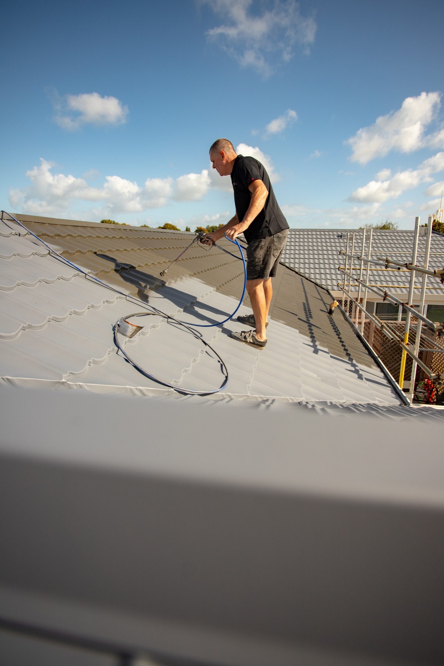 Roof coating being spray applied on a residential roof